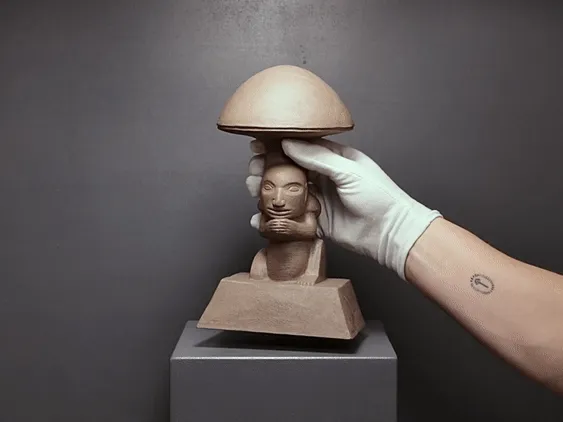 Olmec Prayer, held in a white-gloved hand